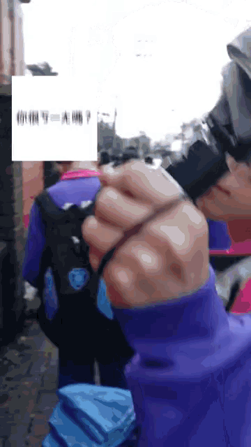 a person in a purple sweatshirt holds a camera in their hand