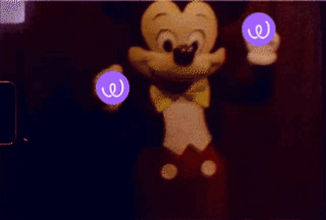 a mickey mouse doll is holding two purple balls