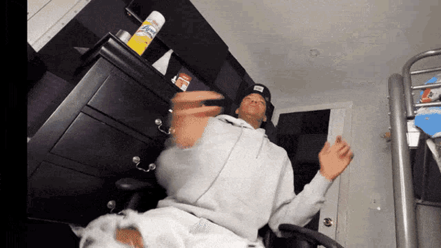 a man is sitting in front of a dresser with a can of clorox spray on top of it