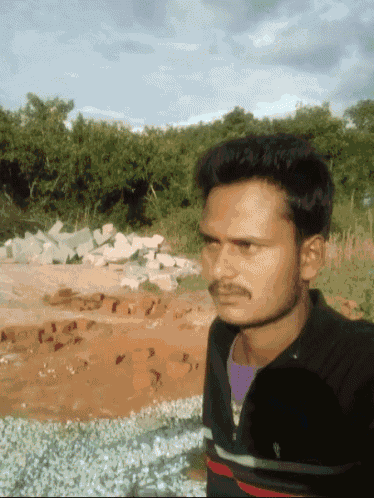 a man with a mustache is standing in front of a pile of bricks