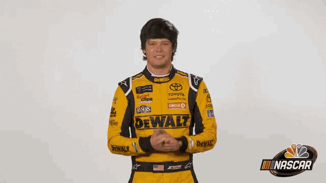 a man in a yellow and black racing suit is standing in front of a sign that says what ?
