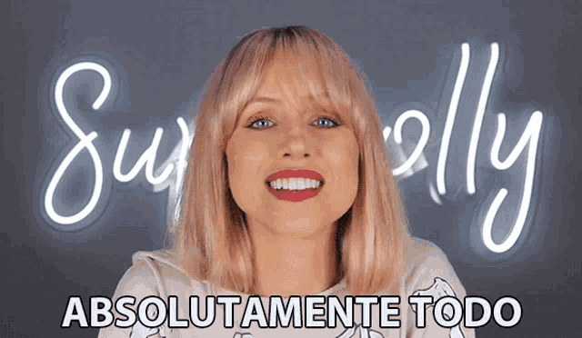 a woman with pink hair is smiling in front of a neon sign that says superally absolutamente todo