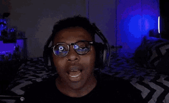 a man wearing headphones and glasses is screaming in front of a microphone with the word handle written on the screen .
