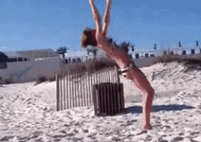 a woman in a bikini is doing a handstand on a sandy beach
