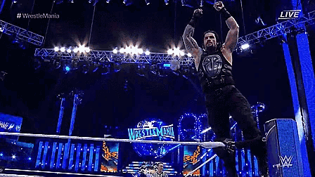 a wrestler is jumping in the air in front of a wrestlemania sign