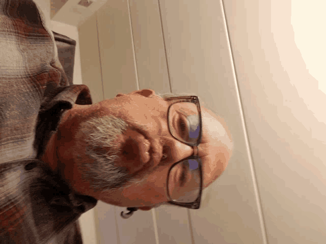 a man wearing glasses and a plaid shirt looks upside down