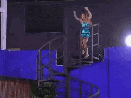 a woman in a blue dress is standing on a set of spiral stairs .