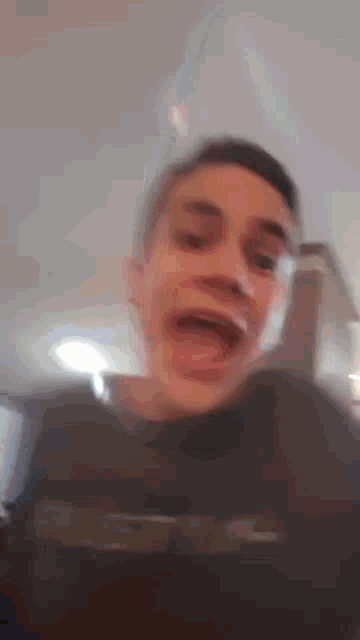 a blurry picture of a young man making a funny face with his mouth open .