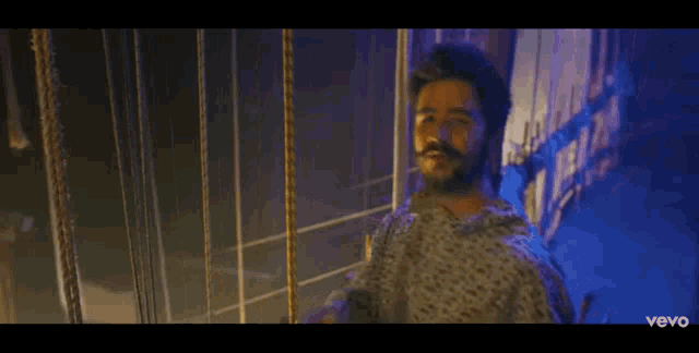 a man with a beard is holding a microphone in his hand and singing into it .