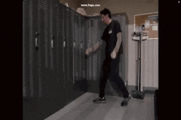 a man is dancing in a locker room in front of lockers .