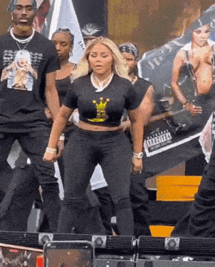 a woman wearing a black crop top with a crown on it is dancing on a stage