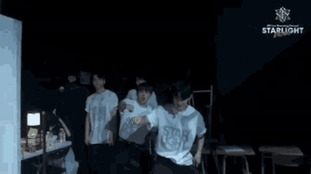 a man wearing a starlight t-shirt stands in a dark room