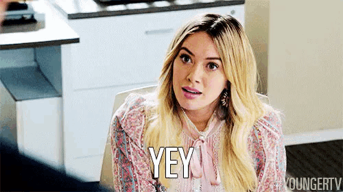 a woman is sitting at a table and saying yey