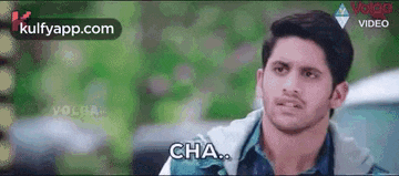 a man is standing in front of a car and saying cha .