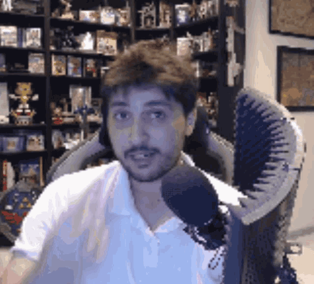 a man with a beard is sitting in a chair with a microphone in front of him .