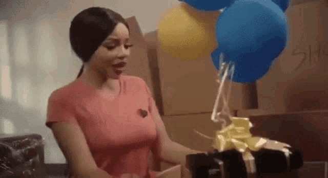 a woman is holding balloons and a gift box .
