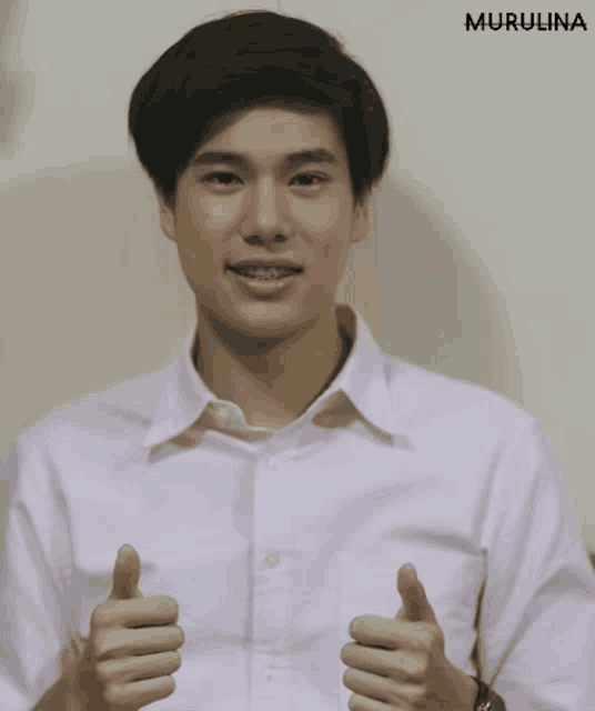 a man in a pink shirt gives a thumbs up sign