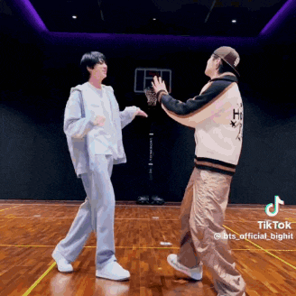 two men are dancing on a wooden floor in a room .