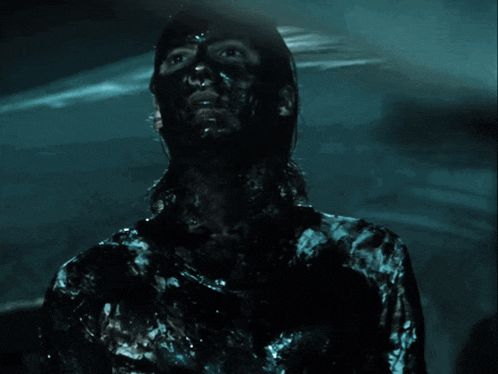 a person with black paint on their face is standing in a dark room