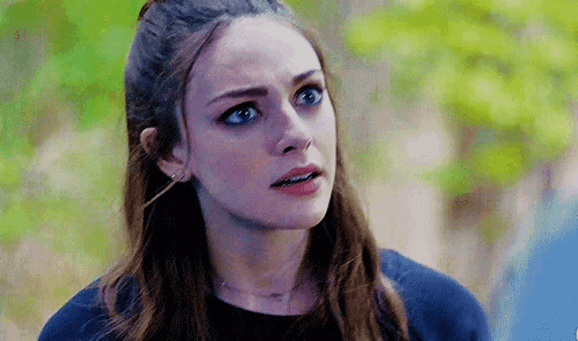 a close up of a woman 's face with blue eyes and a ponytail .
