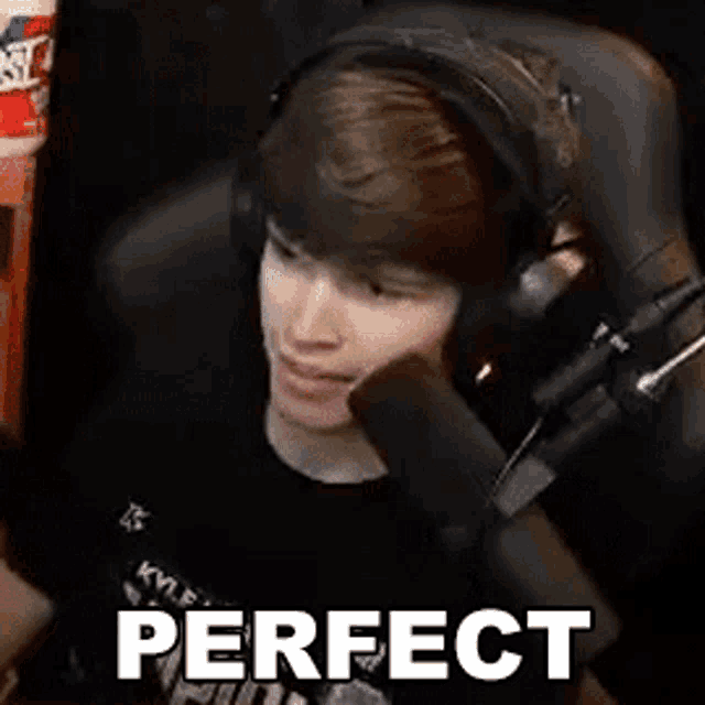 a young man wearing headphones is sitting in front of a microphone and making a face .