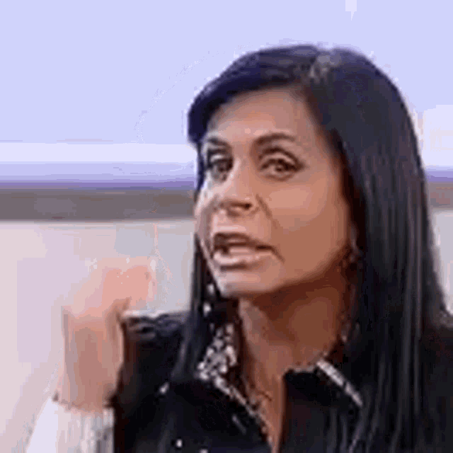a woman with long black hair is making a funny face while talking to someone .