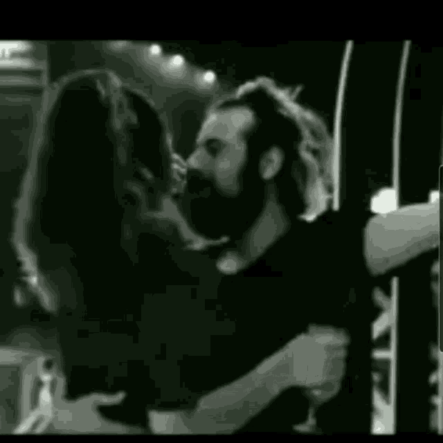 a man and a woman are kissing each other in a black and white photo .