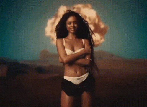 a woman in a bikini is standing in front of an explosion in the desert