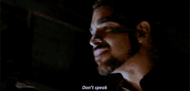 a man with a beard says " don 't speak " while standing next to another man