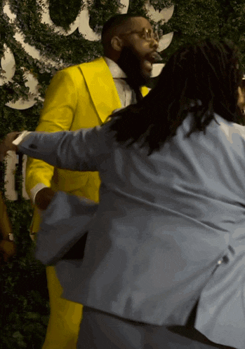 a man in a yellow suit and a man in a blue suit are dancing together