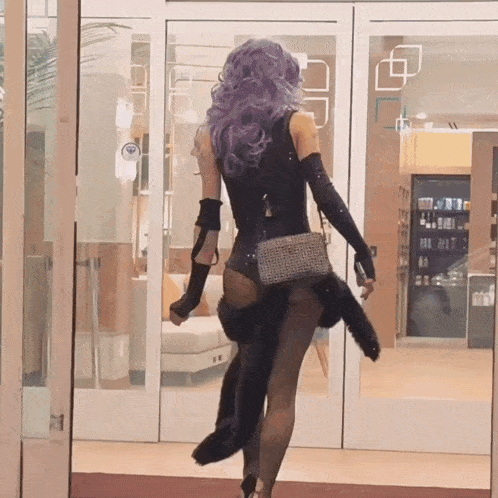 a woman with purple hair is walking through a door