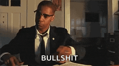 a man in a suit and tie is sitting at a desk with the word bullshit written on the screen .