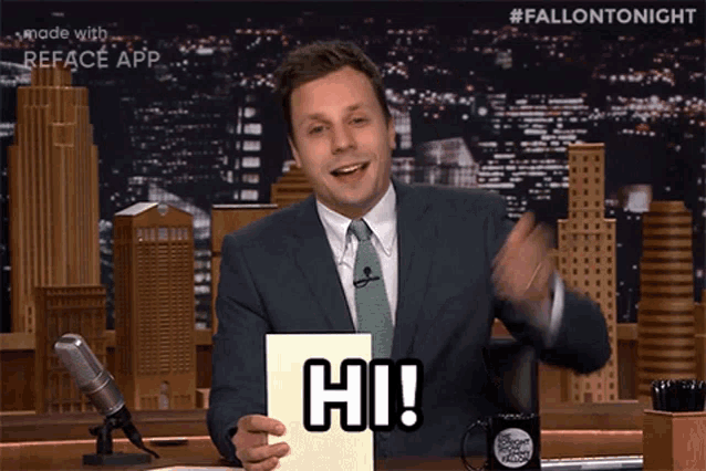a man in a suit and tie is holding a card that says hi on it