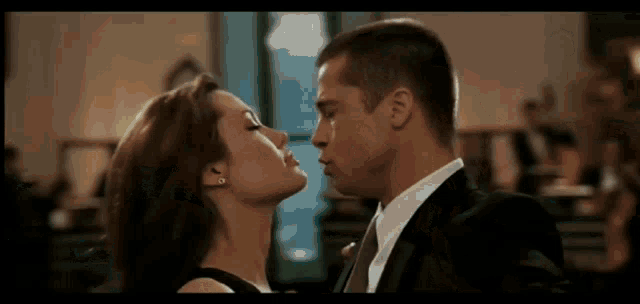 a man in a suit and tie is kissing a woman in a dress .