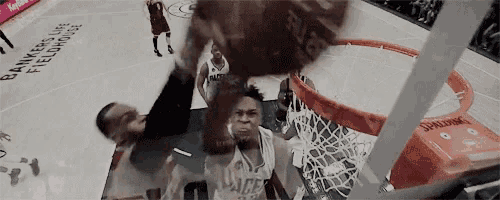 a basketball player is dunking a ball into a hoop .