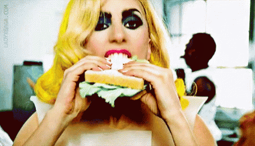a woman with blonde hair is eating a sandwich with a fake face on it .