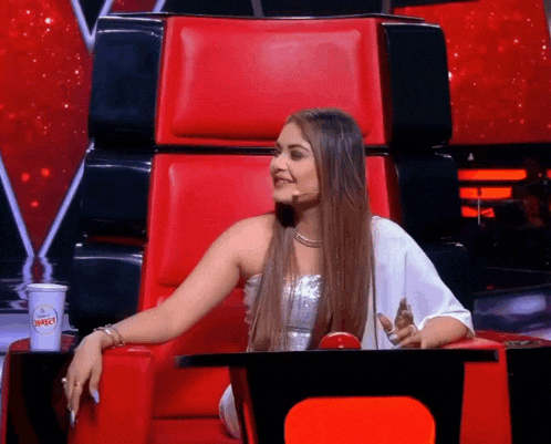 a woman sits in a red chair next to a cup that says juice