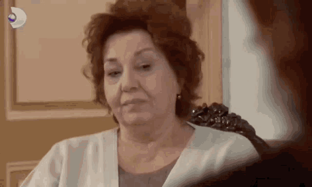 an older woman is sitting in a chair and looking at the camera