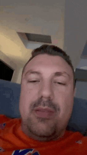 a man with a beard and mustache is laying on a couch with his eyes closed .