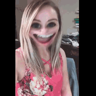 a woman in a pink floral shirt is smiling with a funny face .