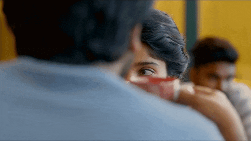 a close up of a woman 's face behind a man 's arm