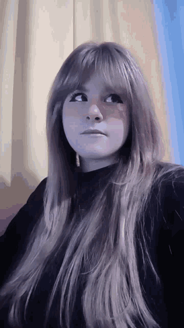 a woman with long blonde hair is wearing a black top