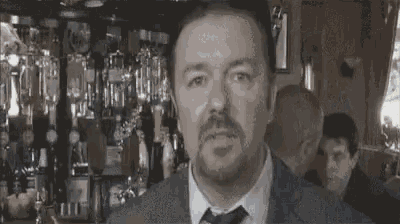 a man in a suit and tie is standing in front of a bar looking at the camera .
