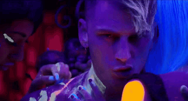 a man with blue hair is holding a purple object in his hand
