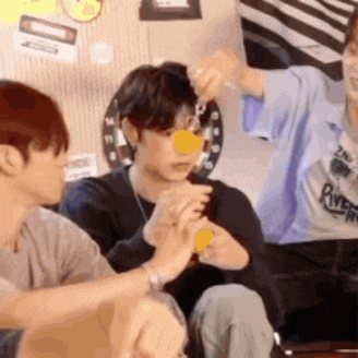 a group of young men are sitting on a couch and one of them is holding a yellow object in his hand .