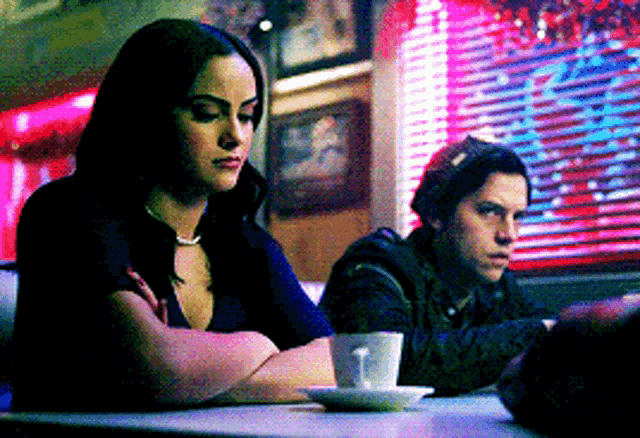 a man and woman are sitting at a table in a diner .