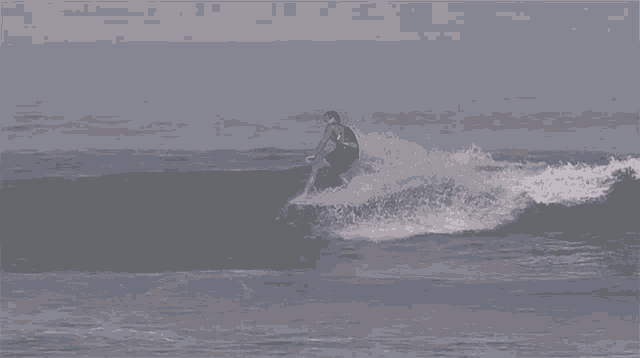 a man in a red shirt is riding a wave on a surfboard in the ocean