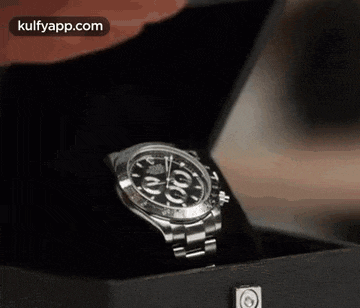 a person is holding a rolex watch in a black box