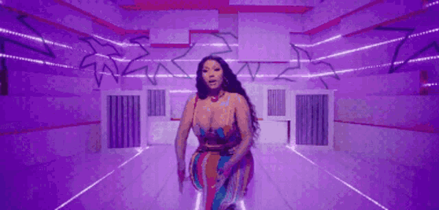 a woman in a colorful dress is standing in a room with purple lights