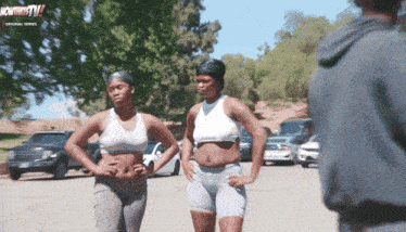 two women standing next to each other in a parking lot in front of a sign that says " howthitty tv "